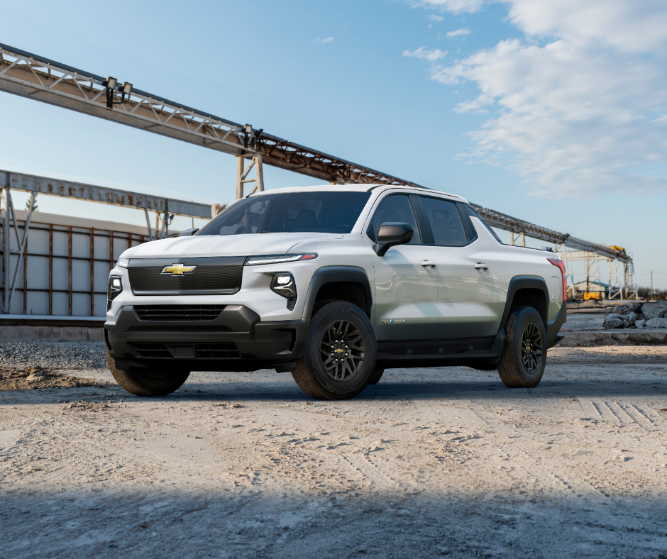 White pickup truck parked on a construction site under a blue sky with scattered clouds.