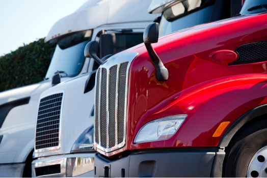 Close-up of a red and white semi-truck parked side by side in bright daylight.