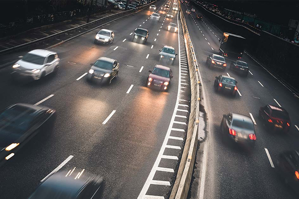 Cars driving on a busy highway at night, headlights and taillights creating a blur of light.
