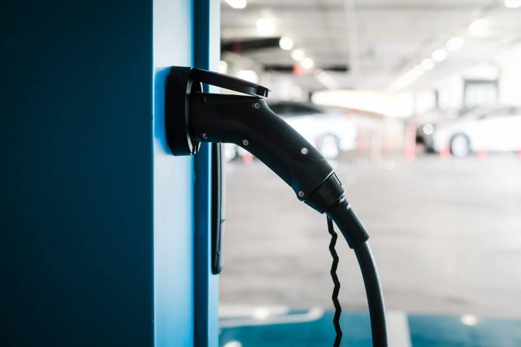Electric car charging station with a connected plug in a parking garage.
