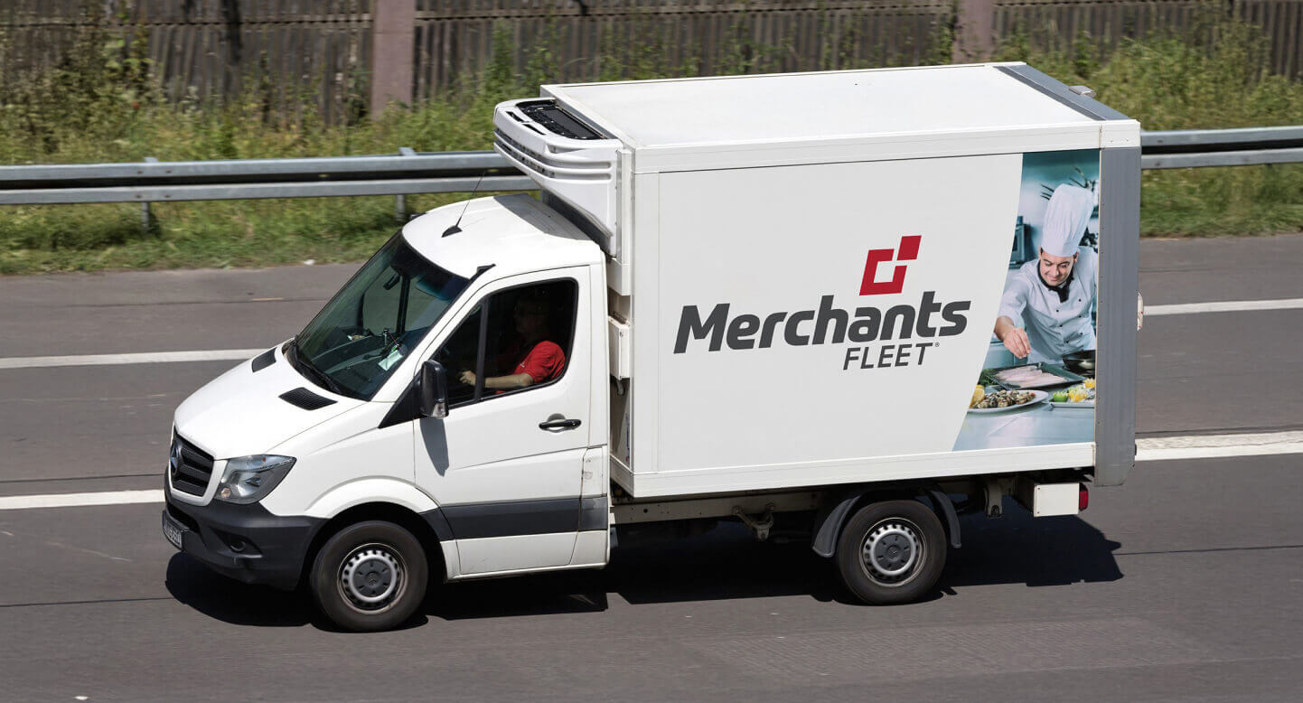 White delivery van with "Merchants Fleet" logo and image of a chef, driving on a highway.